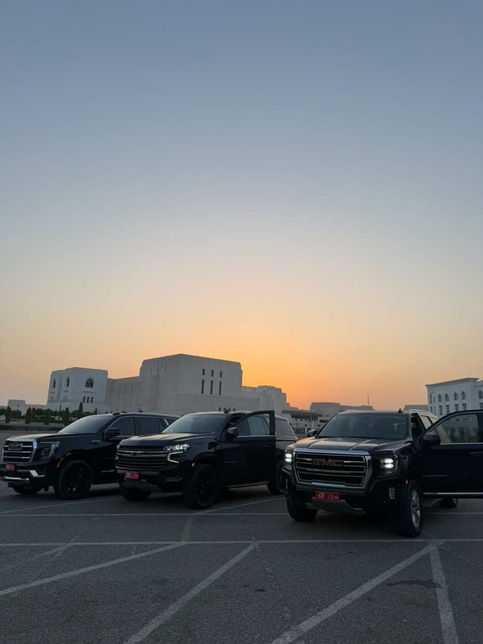 Two GMC SUVs and a Chevrolet SUV parked together at dusk