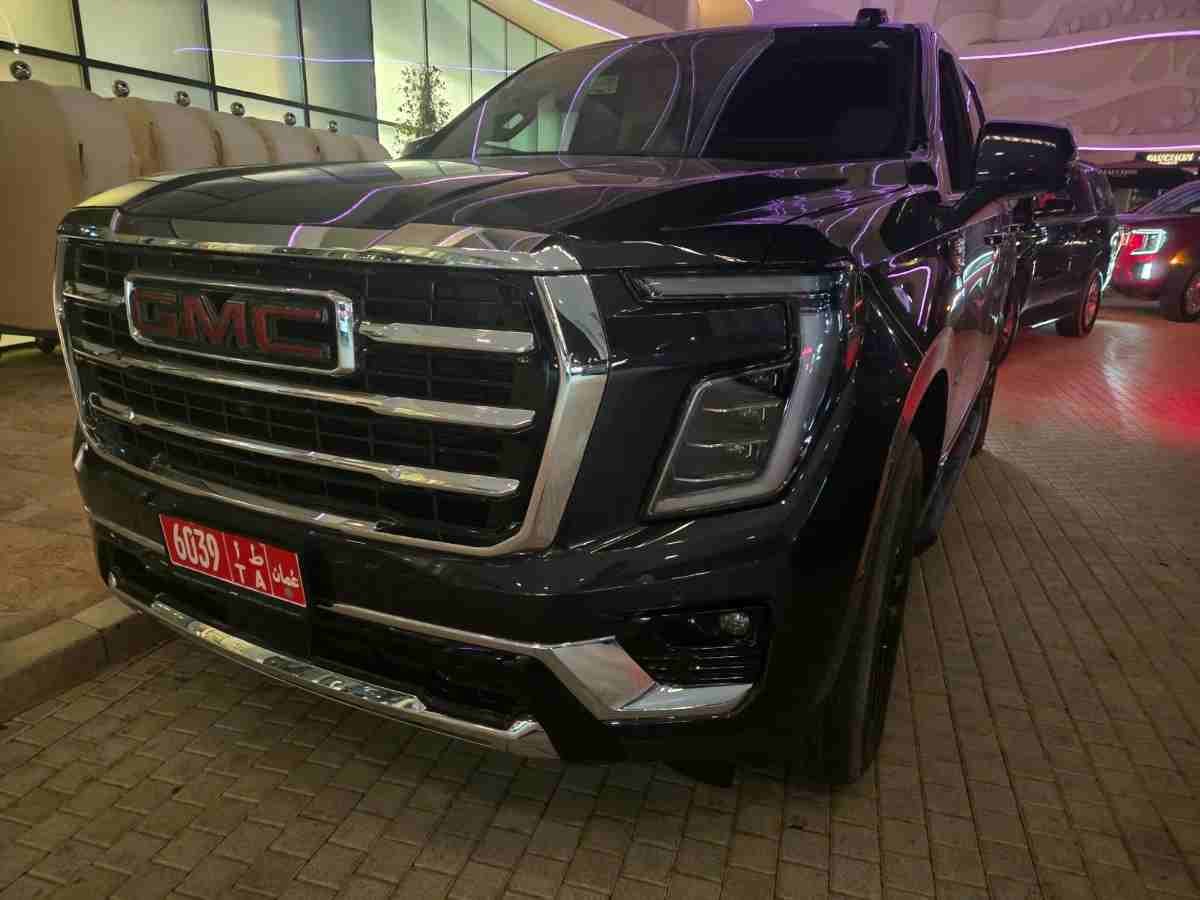 Black GMC SUV parked outside an illuminated building at night